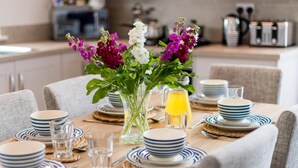 A dining table set with plates, glasses, and a vase with flowers. - 3 Bed in Bideford (oc-64410) (Northam)