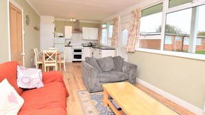 Un espacio habitable compacto con kitchenette, un sofá, una mesita de centro y vistas al exterior.