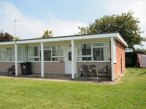 A single-story building with a covered patio area, a trash bin, and a bench. - 2 Bed in Mundesley (oc-kt153) (Mundesley)