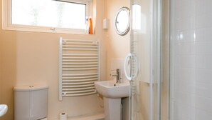 Un baño con inodoro, lavabo, ducha y ventana.