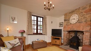 Un salón acogedor con chimenea, televisor, sofá y ventana con cortinas.
