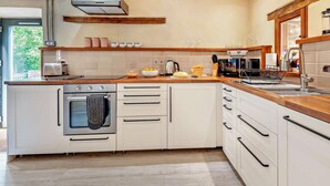 Una cocina moderna con horno empotrado, cafetera y lavamanos.