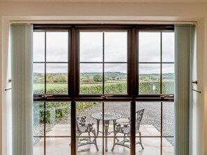 Ein Zimmer mit großem Fenster, einer Tür und einer Terrasse mit Gartenmöbeln.
