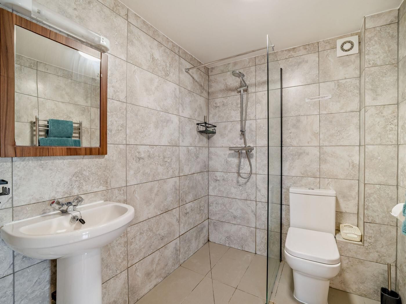 A bathroom with a sink, toilet, shower, and a mirror.