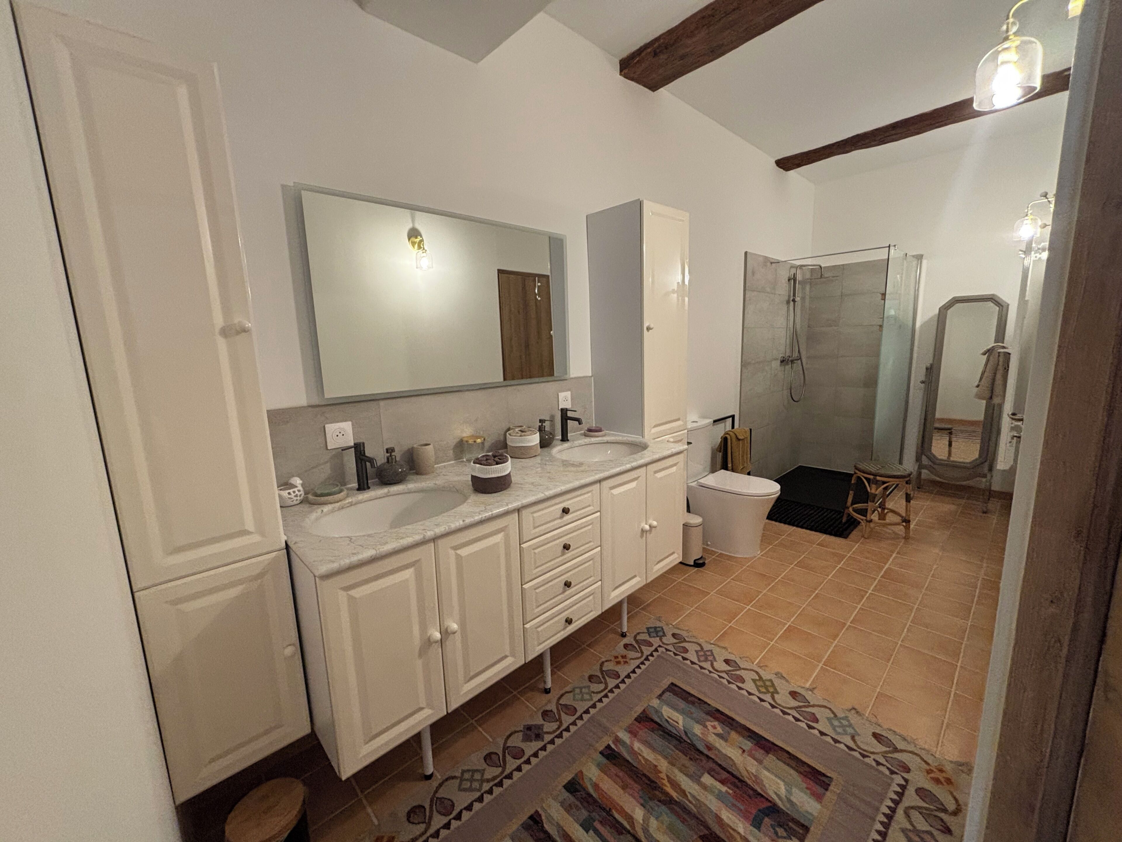 Une salle de bain avec deux lavabos, des toilettes, une douche et un miroir.