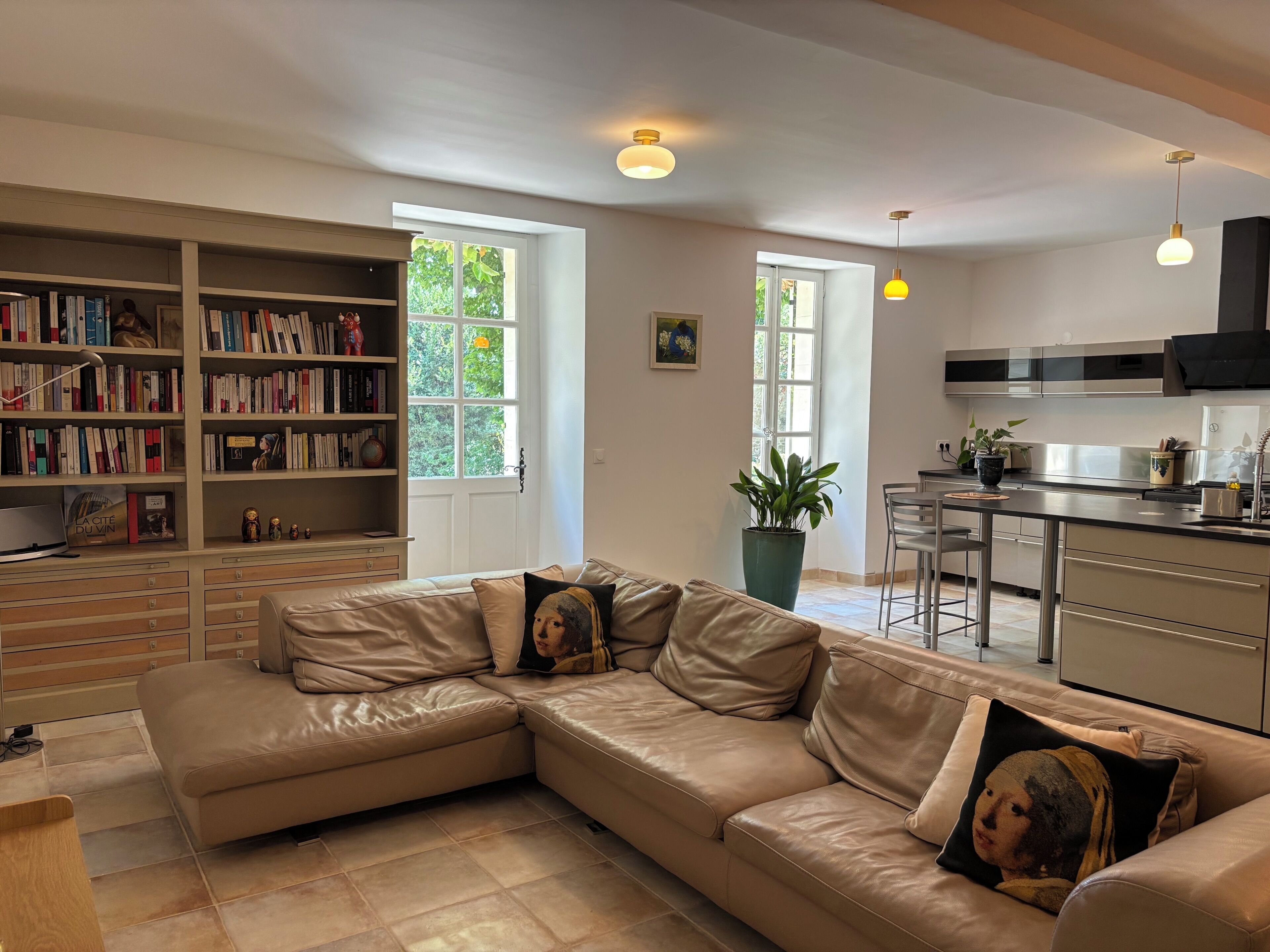 En moderne stue med en lædersofa, en reol og et køkkenområde.