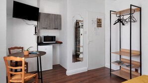 Une petite cuisine équipée comprenant un four à micro-ondes, un petit réfrigérateur et un téléviseur à écran plat fixé au mur.