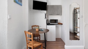 Une cuisine compacte équipée d’un four à micro-ondes, d’un petit réfrigérateur et d’un coin repas avec une table et des chaises.