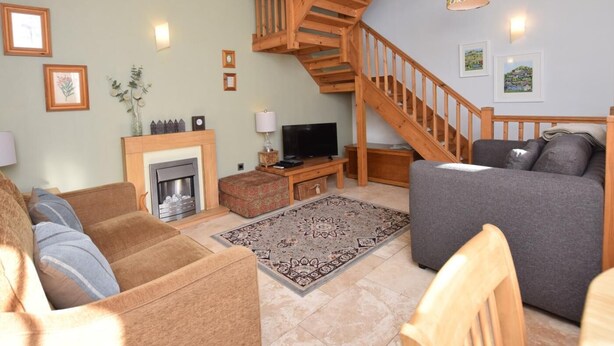 Ein Wohnzimmer mit Kamin, einer Couch, einem Fernseher und einer Holztreppe.