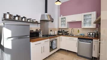 A modern kitchen with stainless steel appliances, white cabinetry, and pendant lighting.