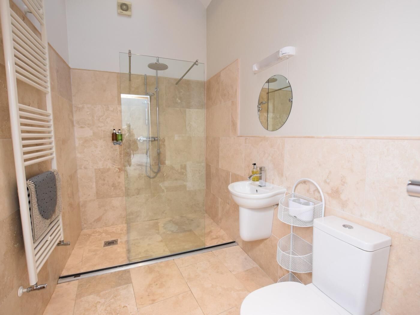 A modern bathroom with a glass-enclosed shower, a white sink, a toilet, and a towel rack.