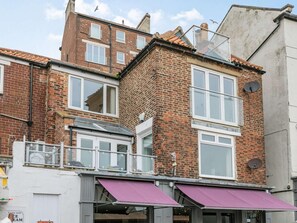 Un bâtiment en briques de deux étages, doté d’un toit plat, de grandes fenêtres et d’une antenne parabolique bien visible.