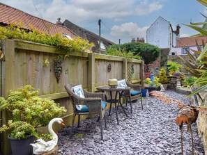 Un espace patio aménagé avec des meubles en osier, une table et des plantes en pot.