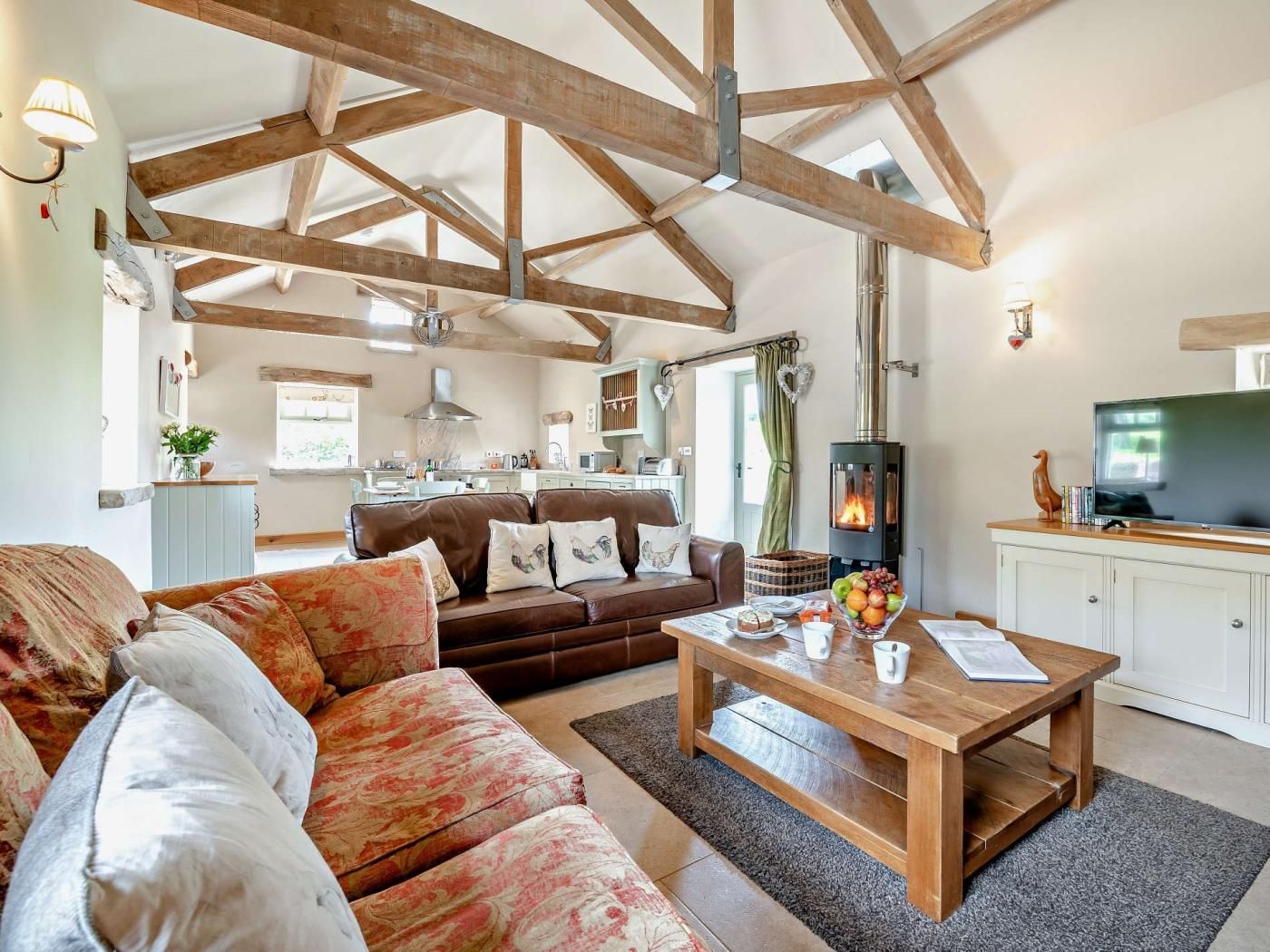 A spacious living room with a high ceiling, a fireplace, a television, and a cozy seating area.