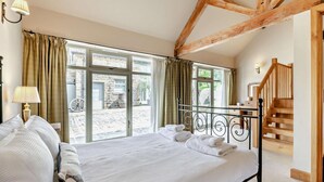 Un dormitorio con una cama grande, una escalera de madera y vistas al exterior.