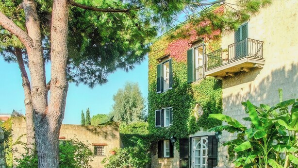 A two-story building with a garden, a tree, and a bench. - Villa Giulia (Campania)