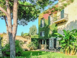 A two-story building with a garden, a tree, and a bench. - Villa Giulia (Campania)