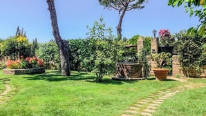 A garden with a stone pathway, a large tree, and a brick structure. - Villa Giulia (Campania)