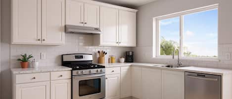 A modern kitchen with white cabinetry, a stainless steel stove, and a dishwasher.