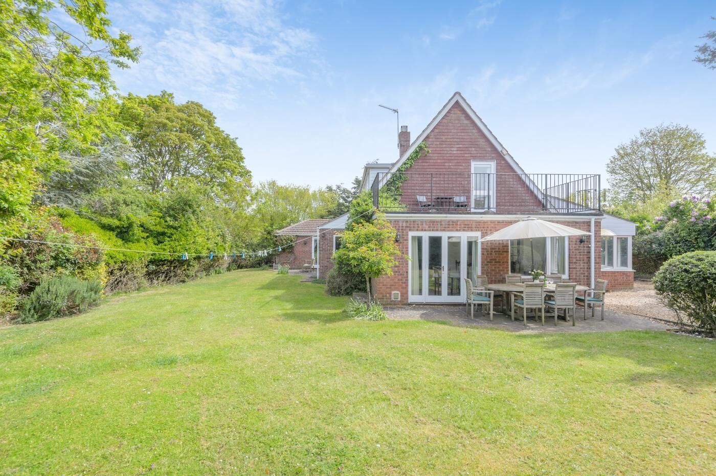 A two-story house with a patio area, a brick exterior, and a garden.