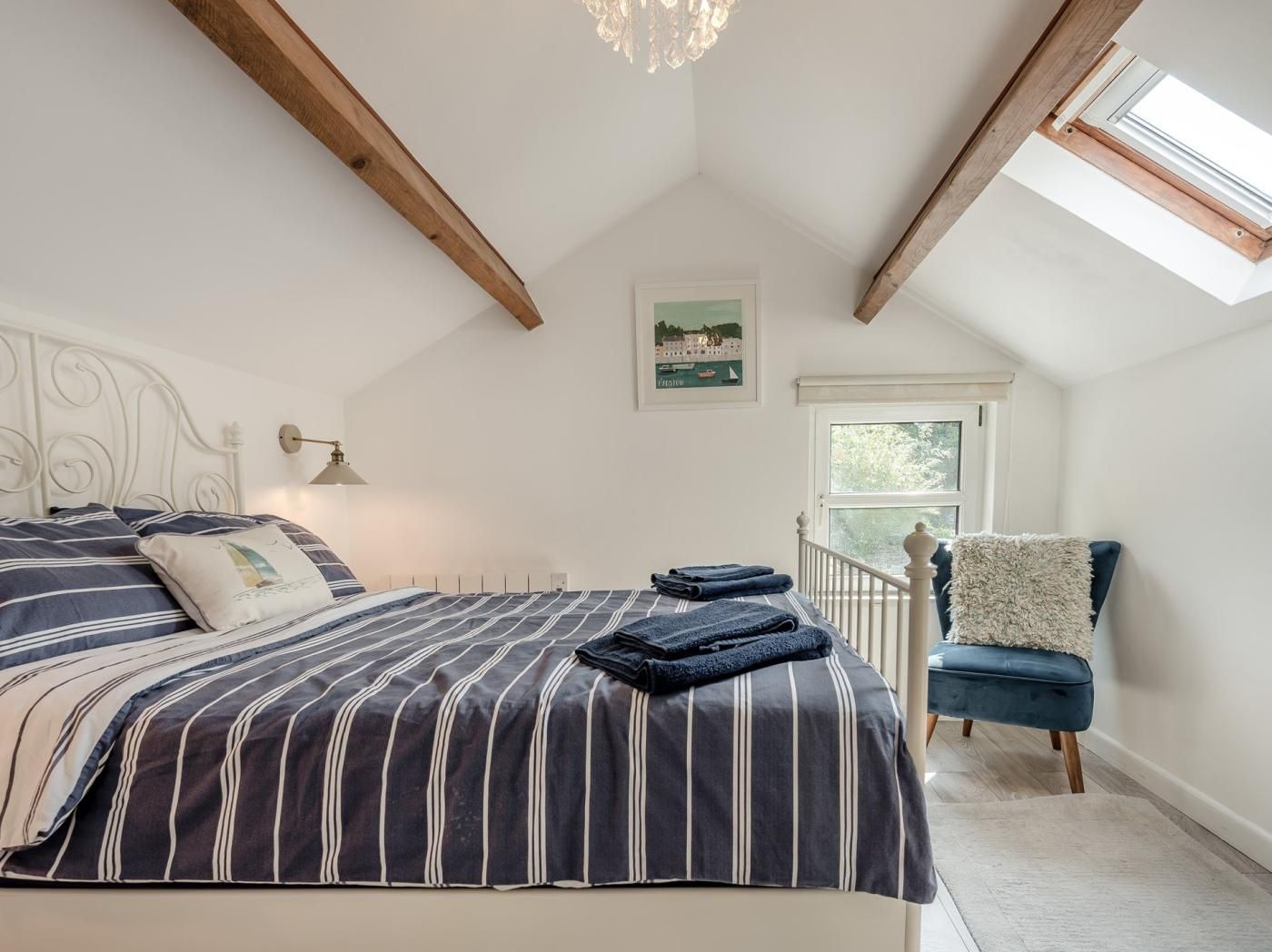 Une chambre à coucher avec un lit, une chaise, une fenêtre et un lustre.