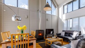 Ein modernes Wohnzimmer mit Kamin, einer Couch, einem Esstisch mit Stühlen und einem Fernseher.