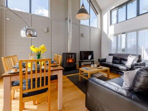 Ein modernes Wohnzimmer mit Kamin, einer Couch, einem Esstisch mit Stühlen und einem Fernseher.