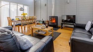 Ein modernes Wohnzimmer mit Kamin, einem Essbereich mit Holzmöbeln und einem großen Fenster.