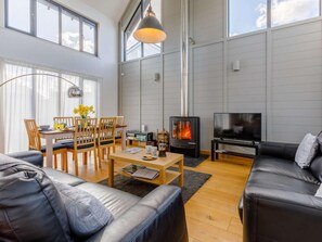 Ein modernes Wohnzimmer mit Kamin, einem Essbereich mit Holzmöbeln und einem großen Fenster.
