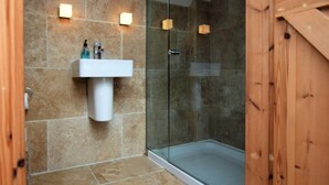 Une salle de bain avec une douche à parois de verre, un lavabo blanc et une porte en bois.