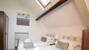 Une chambre avec deux lits, un puits de lumière, un tableau et une armoire en bois.