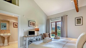 Ein Schlafzimmer mit einem Bett, einem Schreibtisch mit Computer, einem Waschbecken und einem Fenster mit Vorhängen.