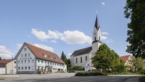 A building with a clock tower, a sign reading 'Zum Schlossherrn,' and a street in front.