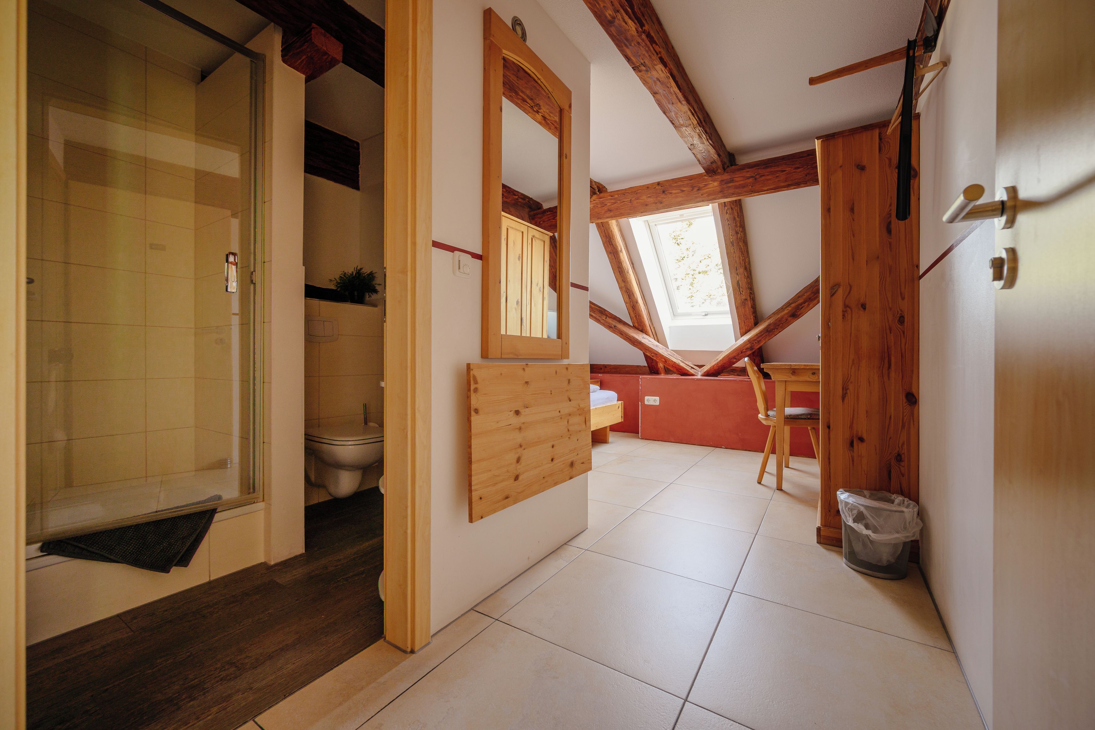 Ein Zimmer mit Holzboden, einem großen Spiegel, einer Toilette, einem Waschbecken und einem Stuhl.