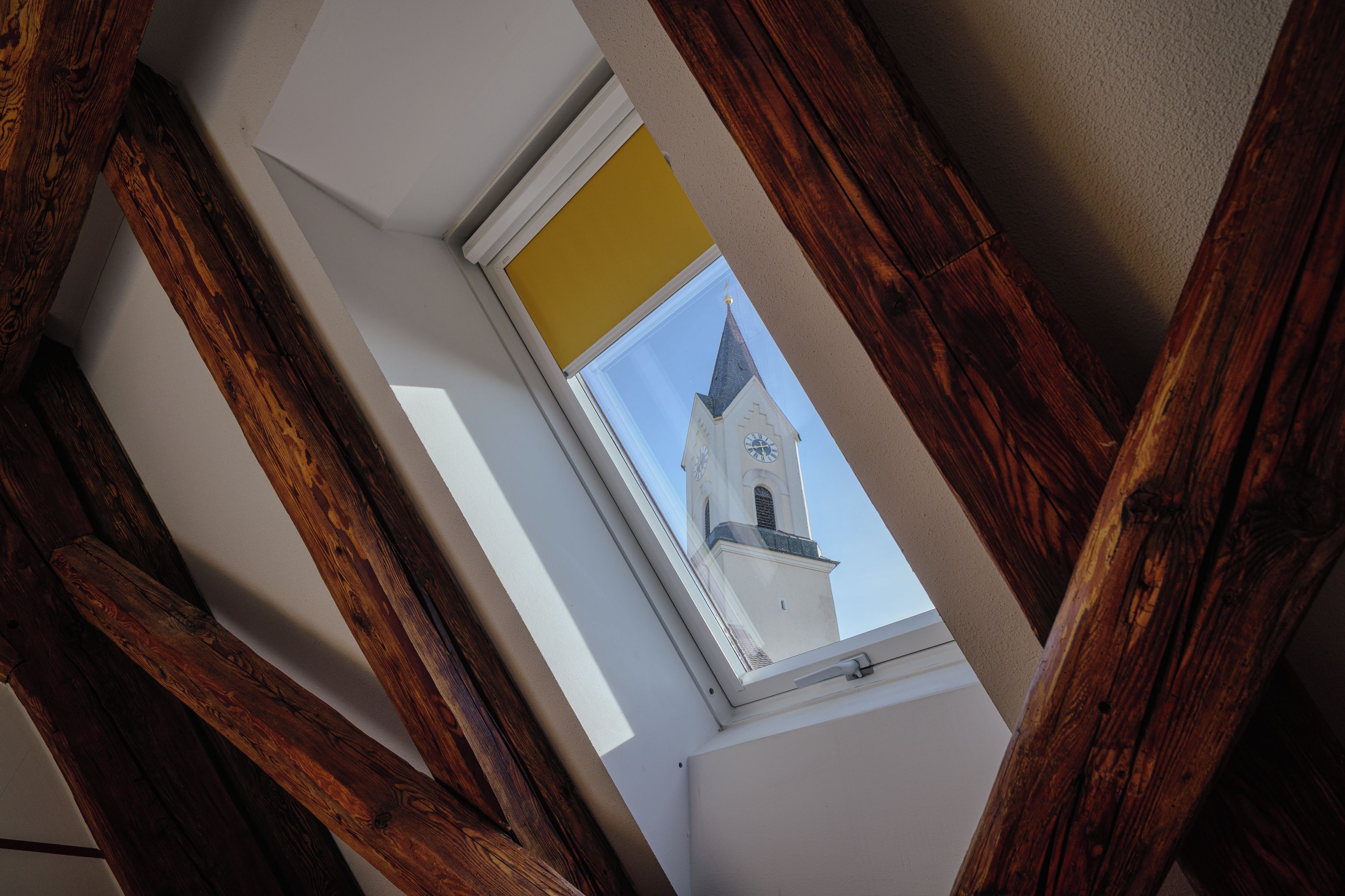A skylight with a view of a church tower.