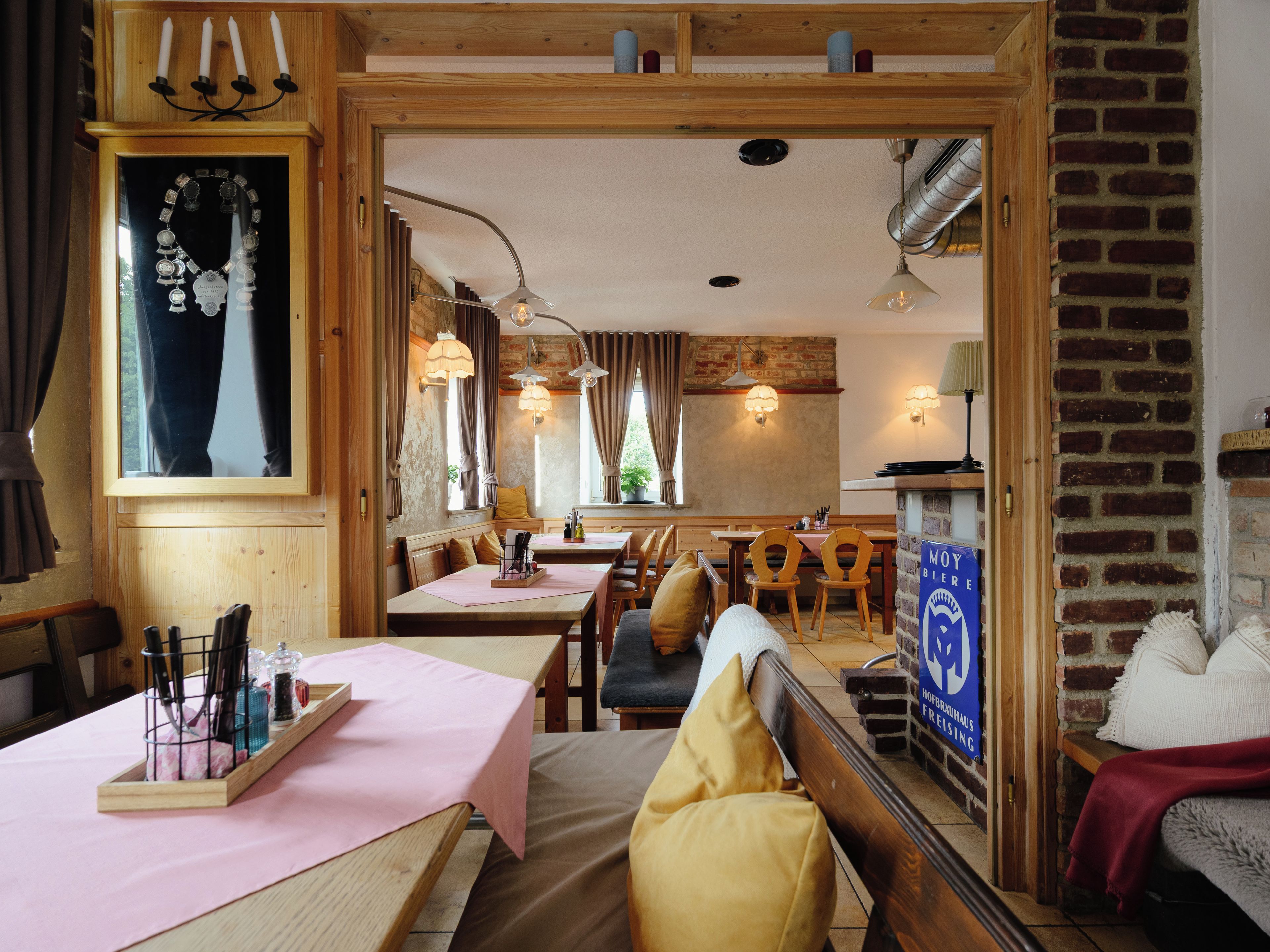 A cozy restaurant with wooden furniture, candlelit ambiance, and a view of the outdoors.
