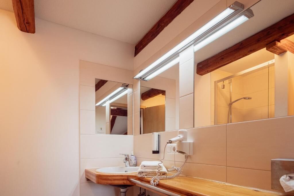 Een moderne badkamer met een houten wastafelmeubel, een grote spiegel en een douchehoek.