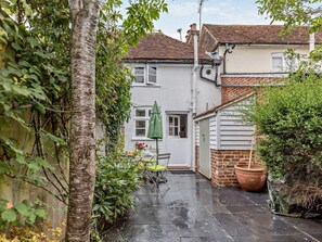 A residential property with a paved patio, a green umbrella, and a brick wall. - 1 Bed in Tenterden (oc-66342) (Tenterden)