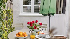 A round table with a bowl of oranges, a glass of orange juice, a white bowl, and a vase with red roses. - 1 Bed in Tenterden (oc-66342) (Tenterden)