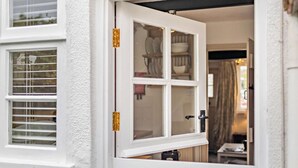 A white door with a glass panel, a window with blinds, and a glimpse of a room with a table and chairs. - 1 Bed in Tenterden (oc-66342) (Tenterden)