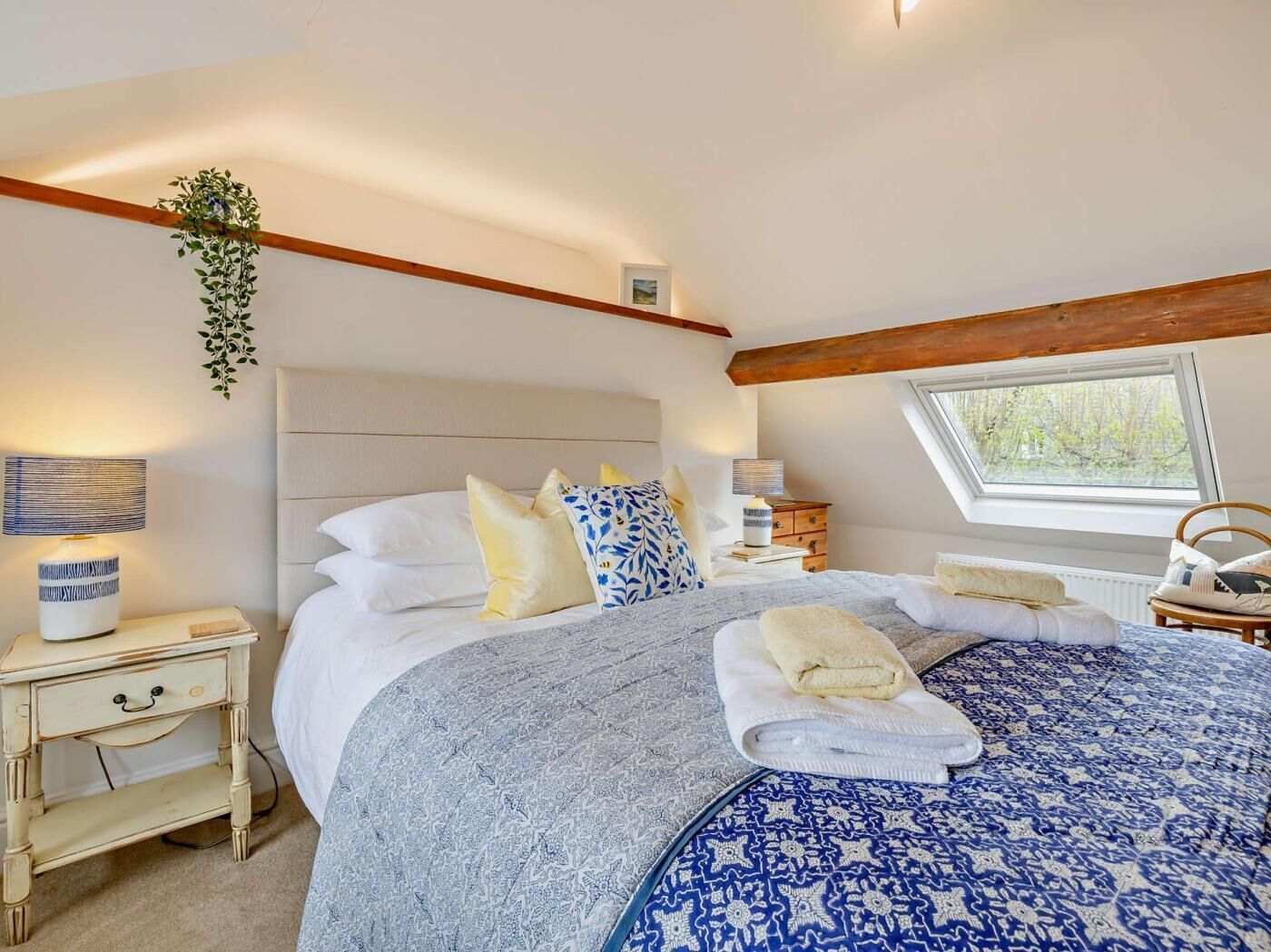 A bedroom with a bed, bedside tables, a window, and a plant.