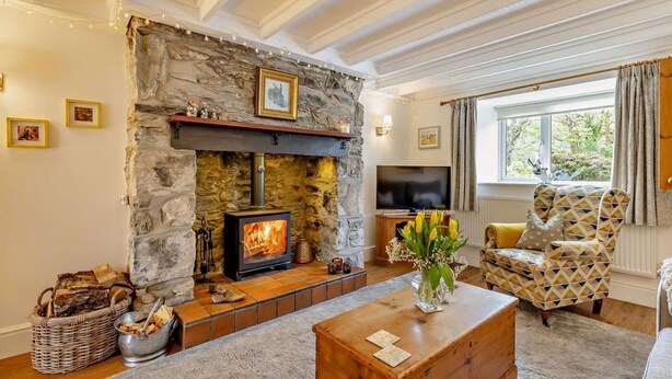 A cozy living room with a stone fireplace, a television, and a patterned armchair. - 2 Bed in Bangor (oc-66276) (Llanddeiniolen)