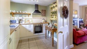 A kitchen with white cabinets, a microwave, a stove, and a dining table. - 2 Bed in Newcastle Upon Tyne (oc-66305) (Otterburn)