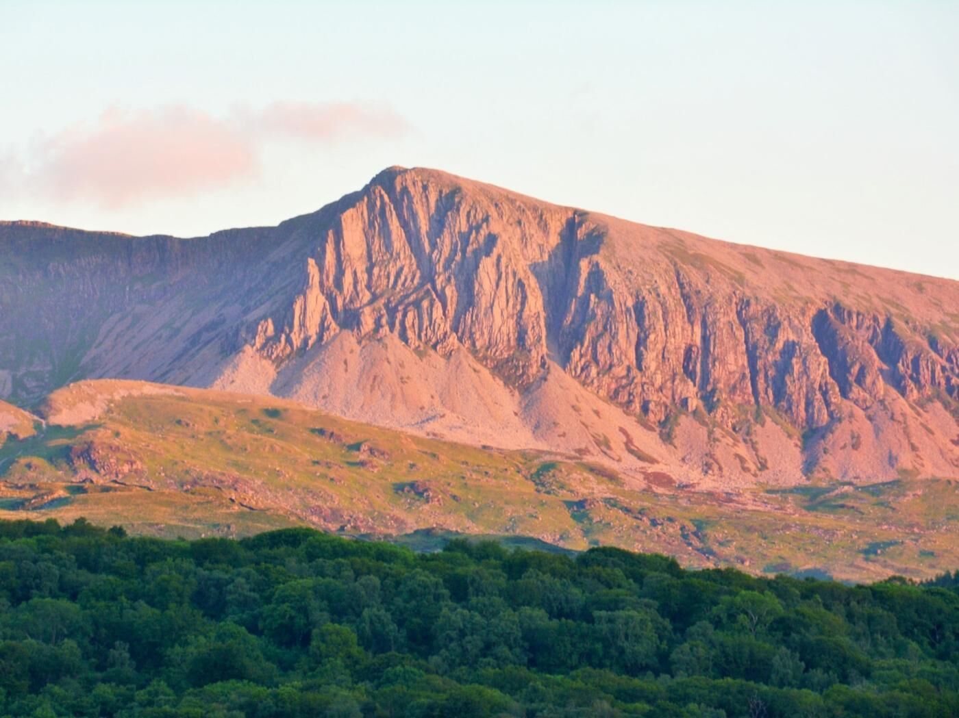 Paisagem montanhosa com vegetação no primeiro plano e um pico rochoso.