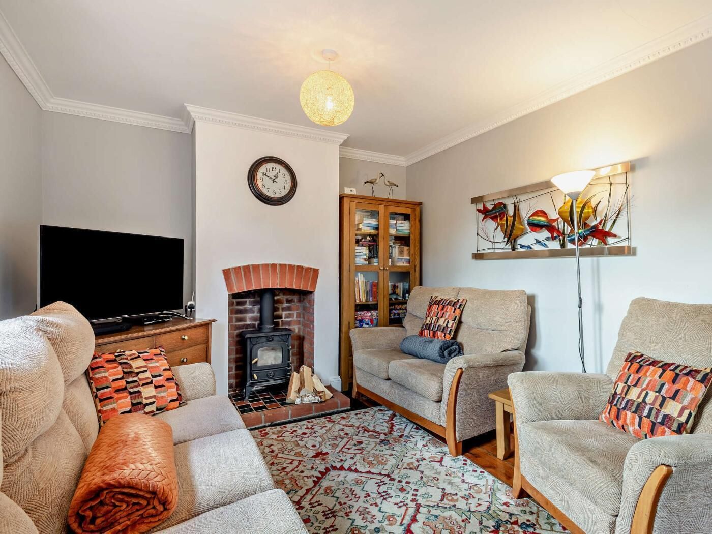 A living room with a fireplace, a television, a bookshelf, and a sofa.