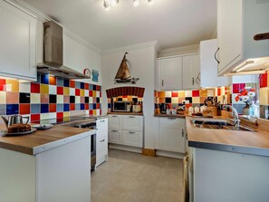 A kitchen with white cabinets, a colorful tile backsplash, a microwave, and a sink. - 3 Bed in Norwich (oc-66597) (Trimingham)