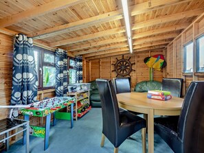 A cozy room with a wooden ceiling, a round table, black chairs, a foosball table, and a sailboat decoration. - 3 Bed in Norwich (oc-66597) (Trimingham)