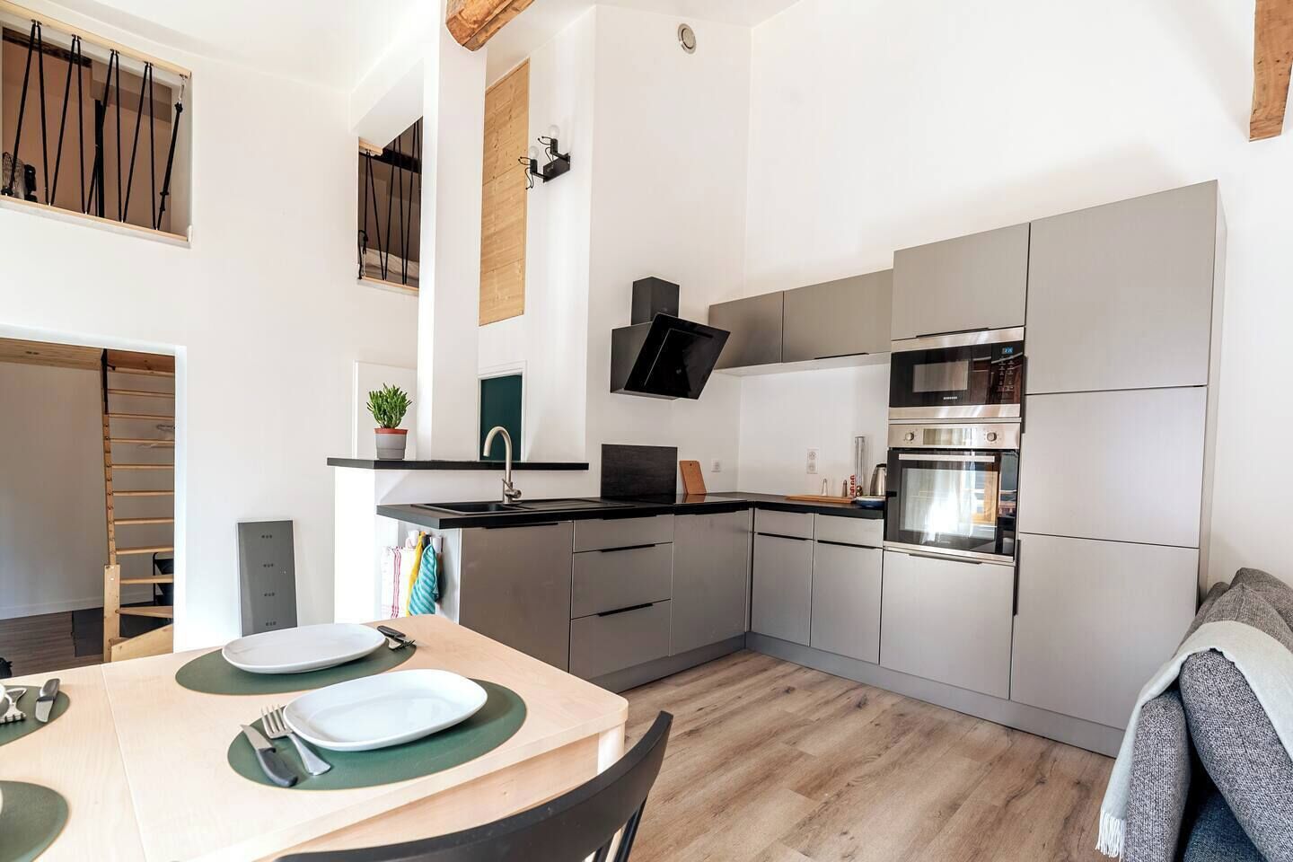 A modern kitchen with a built-in oven, a sink, and a dining area with a table set for two.