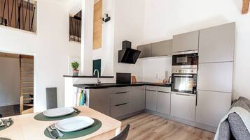 A modern kitchen with a built-in oven, a sink, and a dining area with a table set for two.