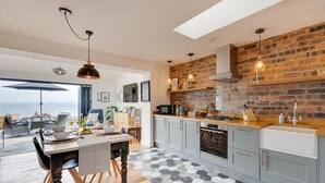 Een moderne keuken met een bakstenen muur, houten vloer en een eethoek met uitzicht.
